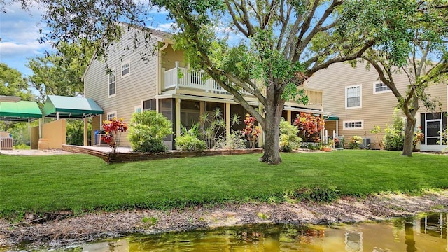 9050 Lake Place Ln, Tampa, FL 33634 - rear view of property featuring a sunroom, a balcony, and a yard