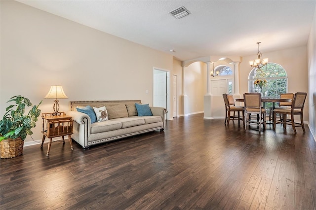 5109 Hartwell Loop, Land O Lakes, FL 34638 - living room featuring arched walkways, dark wood-style floors, ornate columns, a chandelier, and baseboards