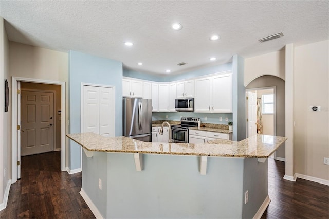 5109 Hartwell Loop, Land O Lakes, FL 34638 - kitchen featuring appliances with stainless steel finishes, arched walkways, dark wood-style floors, a kitchen breakfast bar, and recessed lighting