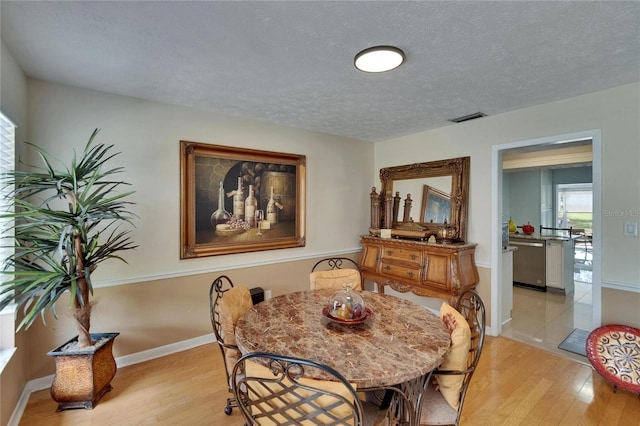 2219 Summit View Dr, Valrico, FL 33596 - dining room with light wood-style flooring, a textured ceiling, and baseboards