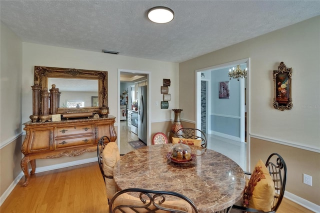 2219 Summit View Dr, Valrico, FL 33596 - dining space with a textured ceiling, light wood finished floors, baseboards, and a chandelier