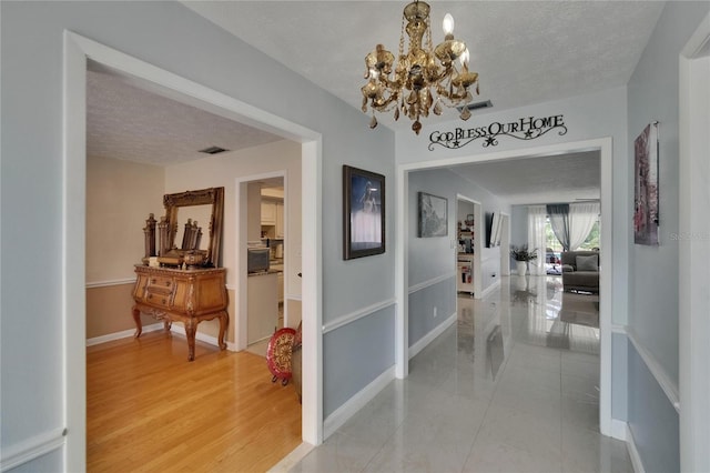 2219 Summit View Dr, Valrico, FL 33596 - hallway with a chandelier, baseboards, a textured ceiling, and light tile patterned floors