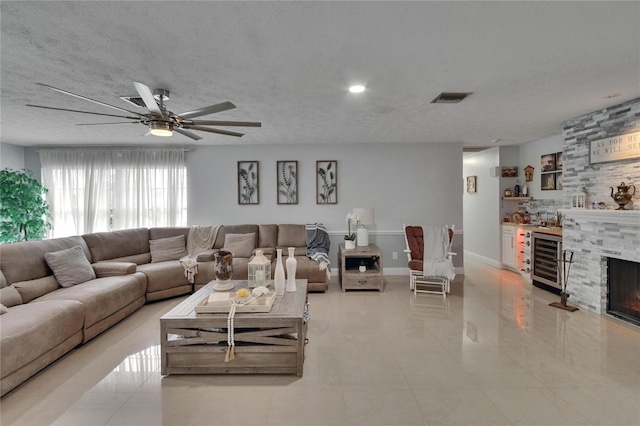 2219 Summit View Dr, Valrico, FL 33596 - living area with wine cooler, ceiling fan, a textured ceiling, light tile patterned floors, and a fireplace