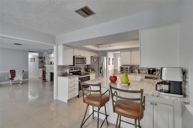 2219 Summit View Dr, Valrico, FL 33596 - kitchen featuring stainless steel appliances, tasteful backsplash, a textured ceiling, a peninsula, and baseboards