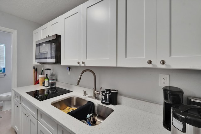 2219 Summit View Dr, Valrico, FL 33596 - kitchen featuring stainless steel microwave, a sink, white cabinetry, light stone counters, and black electric stovetop