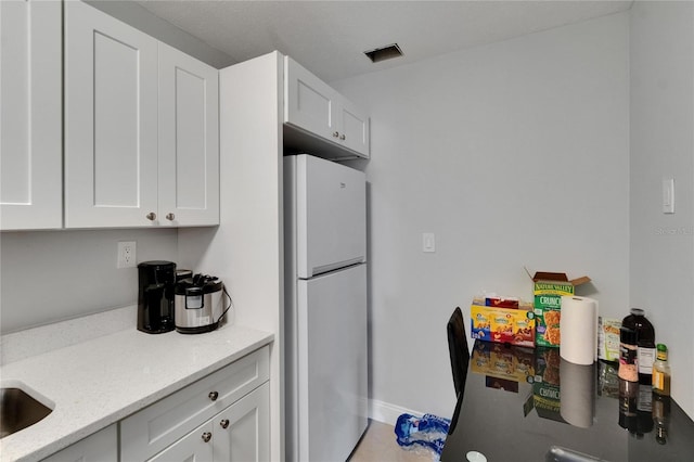 2219 Summit View Dr, Valrico, FL 33596 - kitchen featuring freestanding refrigerator, white cabinetry, and light stone countertops