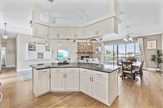 kitchen featuring a fireplace, dark countertops, a center island, light wood finished floors, and ornamental molding