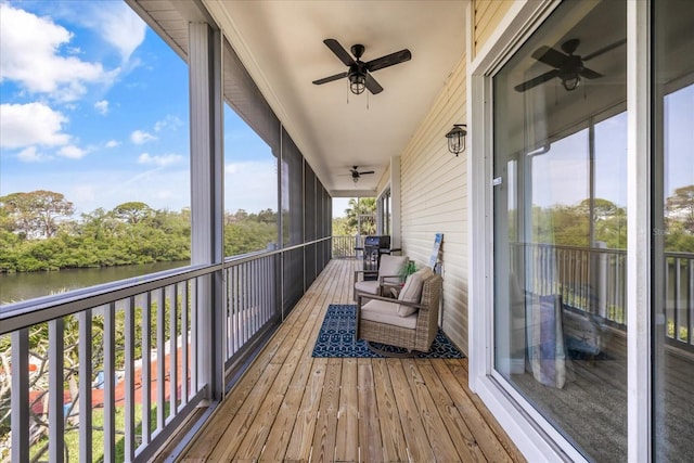 deck with ceiling fan and a water view