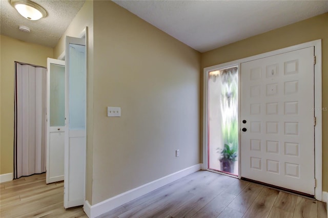 2913 Fig Ct, Palm Harbor, FL 34684 - foyer entrance with light wood-type flooring, baseboards, and a textured ceiling