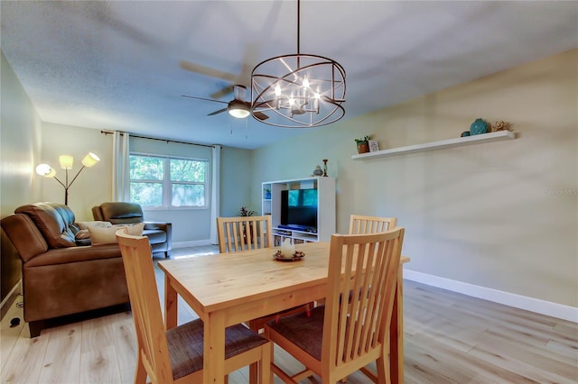 2913 Fig Ct, Palm Harbor, FL 34684 - dining room featuring light wood-style flooring, baseboards, ceiling fan, and a chandelier