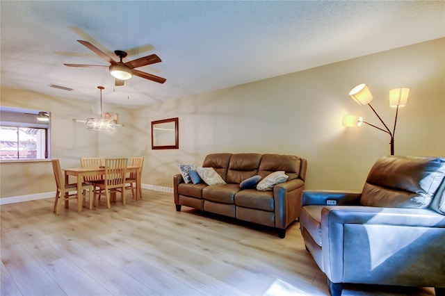 2913 Fig Ct, Palm Harbor, FL 34684 - living room with a ceiling fan, light wood-style flooring, baseboards, a textured ceiling, and a chandelier
