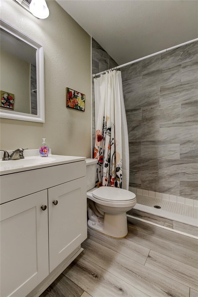 2913 Fig Ct, Palm Harbor, FL 34684 - full bath featuring toilet, tiled shower, vanity, and wood finished floors