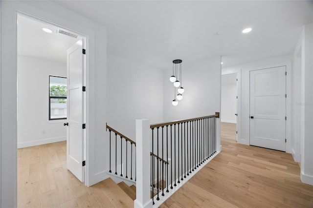 hallway featuring an upstairs landing, light wood finished floors, recessed lighting, and baseboards