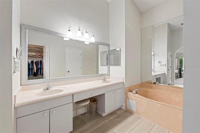 2015 W Del Webb Blvd, Sun City Center, FL 33573 - bathroom with double vanity, a bath, a spacious closet, and wood finished floors
