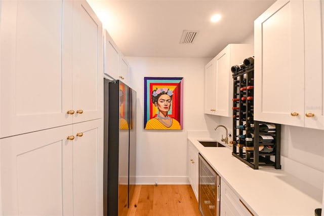 13916 Wellesford Way, Tampa, FL 33624 - kitchen featuring beverage cooler, a sink, baseboards, light wood-type flooring, and light countertops