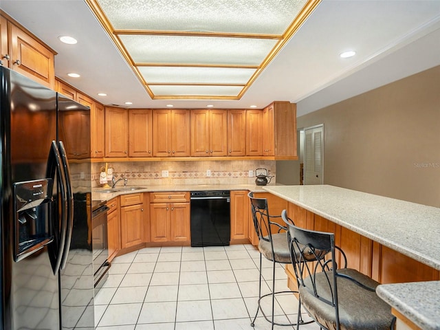 830 S Gulfview Blvd Unit 102, Clearwater Beach, FL 33767 - kitchen featuring black appliances, backsplash, light tile patterned flooring, brown cabinets, and a kitchen bar