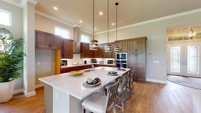 426 Bourganville Dr, Palm Coast, FL 32137 - kitchen featuring french doors, wall chimney range hood, baseboards, hanging light fixtures, and crown molding