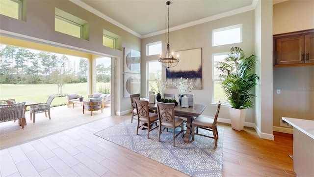 426 Bourganville Dr, Palm Coast, FL 32137 - dining area featuring crown molding, a towering ceiling, a chandelier, light wood finished floors, and baseboards