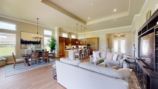 426 Bourganville Dr, Palm Coast, FL 32137 - living area featuring a chandelier, a raised ceiling, french doors, crown molding, and light wood-style flooring