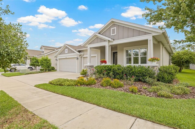 4166 Epic Cv, Land O Lakes, FL 34638 - craftsman-style home with concrete driveway, board and batten siding, an attached garage, stucco siding, and a front yard
