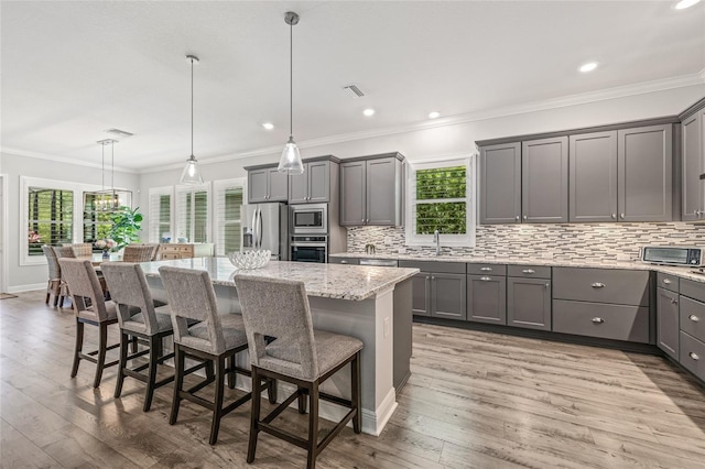 4166 Epic Cv, Land O Lakes, FL 34638 - kitchen featuring stainless steel appliances, gray cabinets, a sink, a center island, and light stone countertops