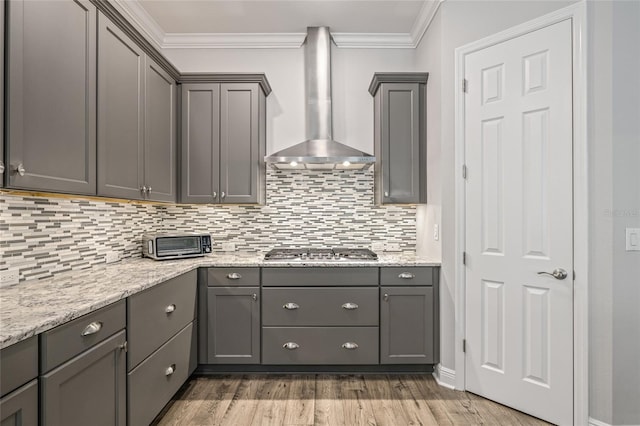 4166 Epic Cv, Land O Lakes, FL 34638 - kitchen featuring wall chimney range hood, stainless steel gas cooktop, gray cabinetry, ornamental molding, and decorative backsplash