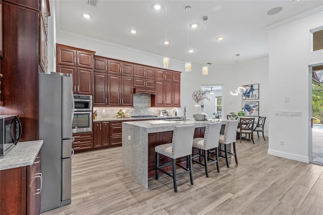 16712 Courtyard Loop, Land O Lakes, FL 34638 - kitchen with stainless steel appliances, a kitchen bar, backsplash, decorative light fixtures, and a kitchen island with sink