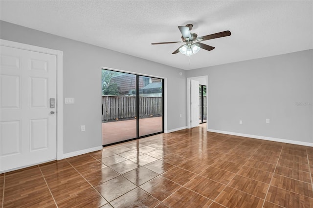 unfurnished room with ceiling fan, a textured ceiling, and baseboards
