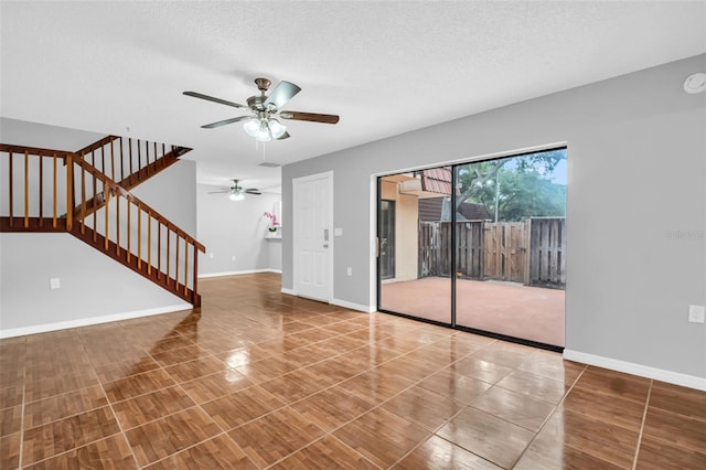 unfurnished living room with a ceiling fan, stairs, baseboards, and a textured ceiling