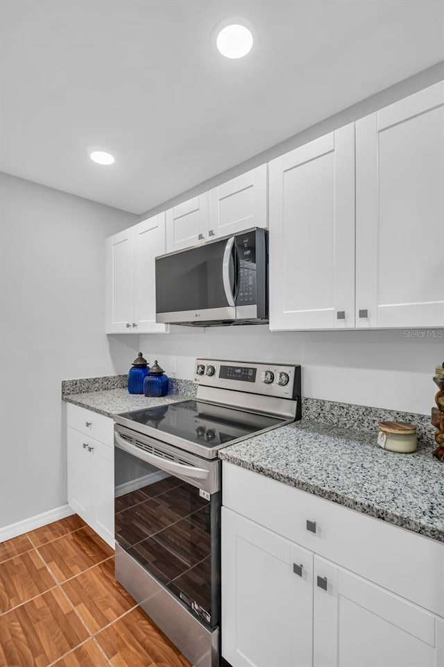 kitchen with appliances with stainless steel finishes, baseboards, white cabinetry, light wood-style flooring, and recessed lighting