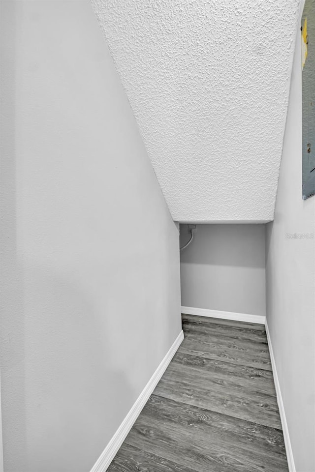 stairway featuring baseboards, wood finished floors, and a textured ceiling