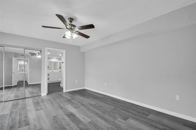 unfurnished bedroom featuring wood finished floors, baseboards, a textured ceiling, a closet, and a ceiling fan