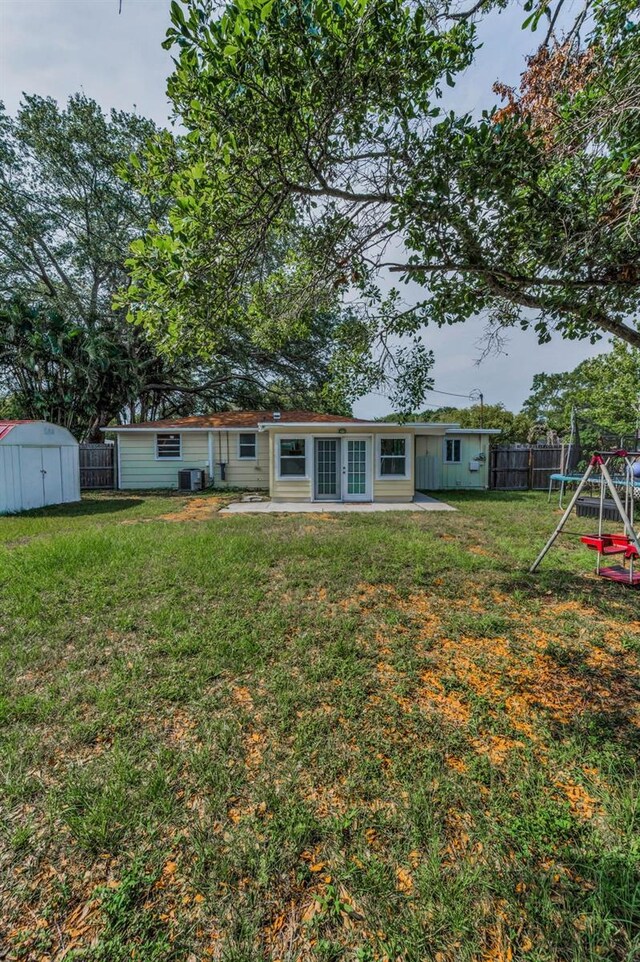 629 Lexington St, Dunedin, FL 34698 - rear view of house featuring a storage unit, a fenced backyard, a playground, a patio area, and french doors