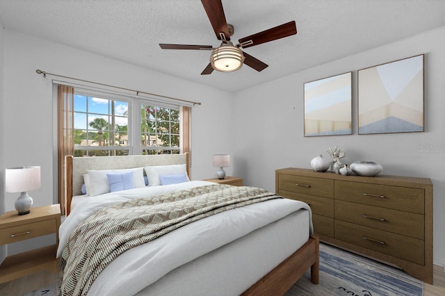 bedroom featuring ceiling fan, a textured ceiling, and wood finished floors