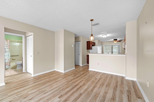 unfurnished living room featuring light wood finished floors, a textured ceiling, a ceiling fan, and baseboards