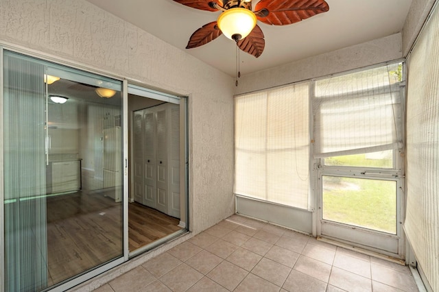 unfurnished sunroom with ceiling fan