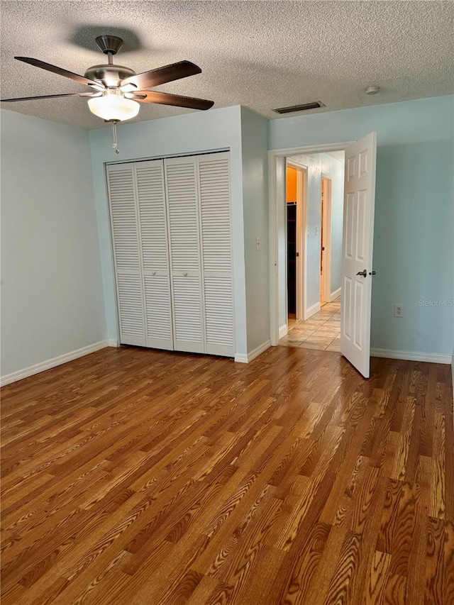 1020 85th Ave N Unit 223, Saint Petersburg, FL 33702 - unfurnished bedroom featuring a textured ceiling, wood finished floors, a closet, a ceiling fan, and baseboards