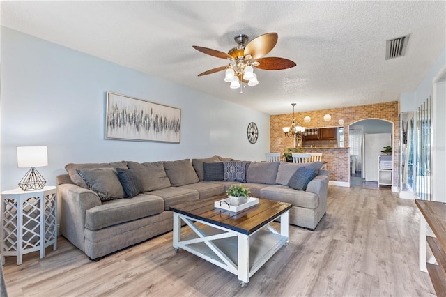 1020 85th Ave N Unit 223, Saint Petersburg, FL 33702 - living room featuring brick wall, arched walkways, a textured ceiling, a ceiling fan, and light wood finished floors