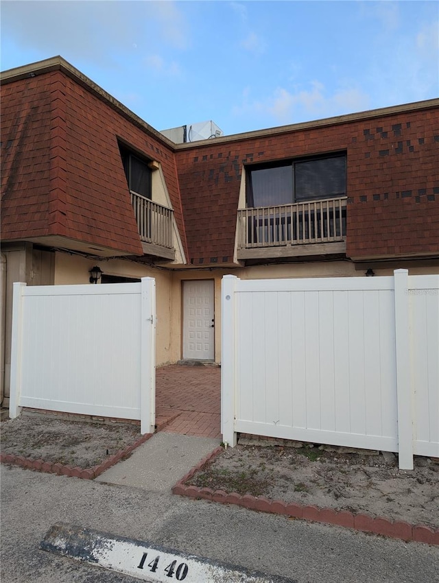 8114 Oak Trace Way Unit D, Tampa, FL 33634 - view of front of house with a balcony, mansard roof, and roof with shingles