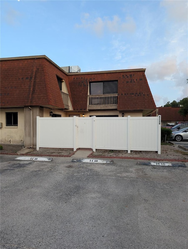 8114 Oak Trace Way Unit D, Tampa, FL 33634 - view of property exterior featuring uncovered parking, mansard roof, and a shingled roof