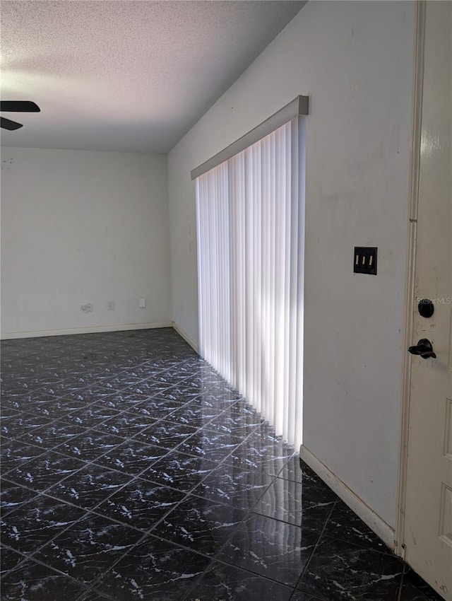 8114 Oak Trace Way Unit D, Tampa, FL 33634 - unfurnished room with marble look tile flooring, ceiling fan, a textured ceiling, and baseboards