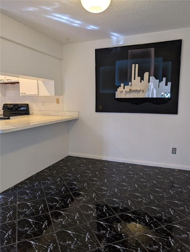 8114 Oak Trace Way Unit D, Tampa, FL 33634 - kitchen with black stove, tasteful backsplash, white cabinets, light countertops, and a textured ceiling