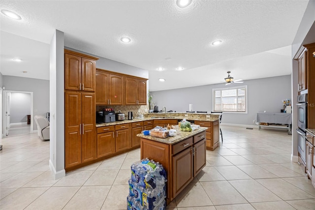 kitchen featuring a peninsula, baseboards, a sink, light tile patterned floors, and a textured ceiling