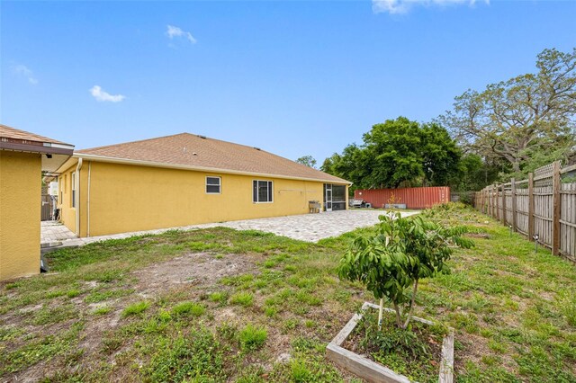 rear view of house with fence, a patio, and stucco siding