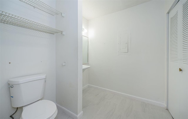 1799 N Highland Ave Unit 106, Clearwater, FL 33755 - half bathroom featuring toilet, electric panel, marble look tile flooring, baseboards, and a closet