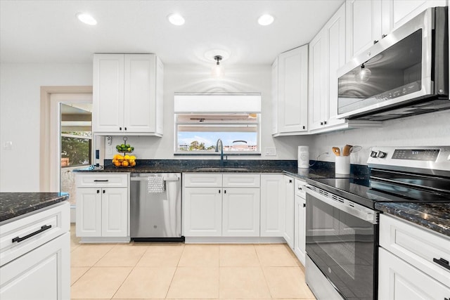 8848 Sunlit Cove Dr NE, Saint Petersburg, FL 33702 - kitchen featuring appliances with stainless steel finishes, a sink, white cabinets, recessed lighting, and dark stone counters