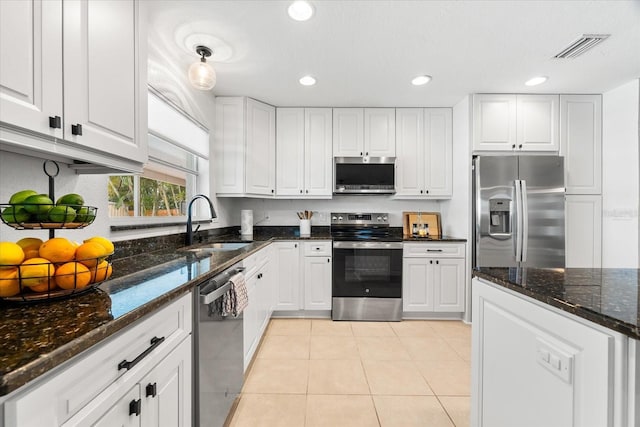 8848 Sunlit Cove Dr NE, Saint Petersburg, FL 33702 - kitchen with stainless steel appliances, a sink, light tile patterned flooring, white cabinetry, and recessed lighting