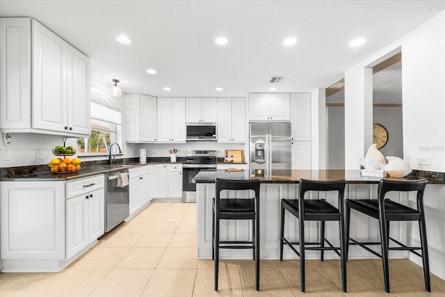 8848 Sunlit Cove Dr NE, Saint Petersburg, FL 33702 - kitchen with stainless steel appliances, a sink, a breakfast bar area, white cabinetry, and recessed lighting