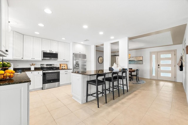 8848 Sunlit Cove Dr NE, Saint Petersburg, FL 33702 - kitchen with appliances with stainless steel finishes, a kitchen breakfast bar, light tile patterned flooring, white cabinetry, and recessed lighting