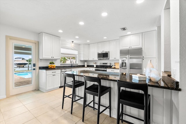 8848 Sunlit Cove Dr NE, Saint Petersburg, FL 33702 - kitchen with stainless steel appliances, a peninsula, white cabinets, a breakfast bar area, and recessed lighting